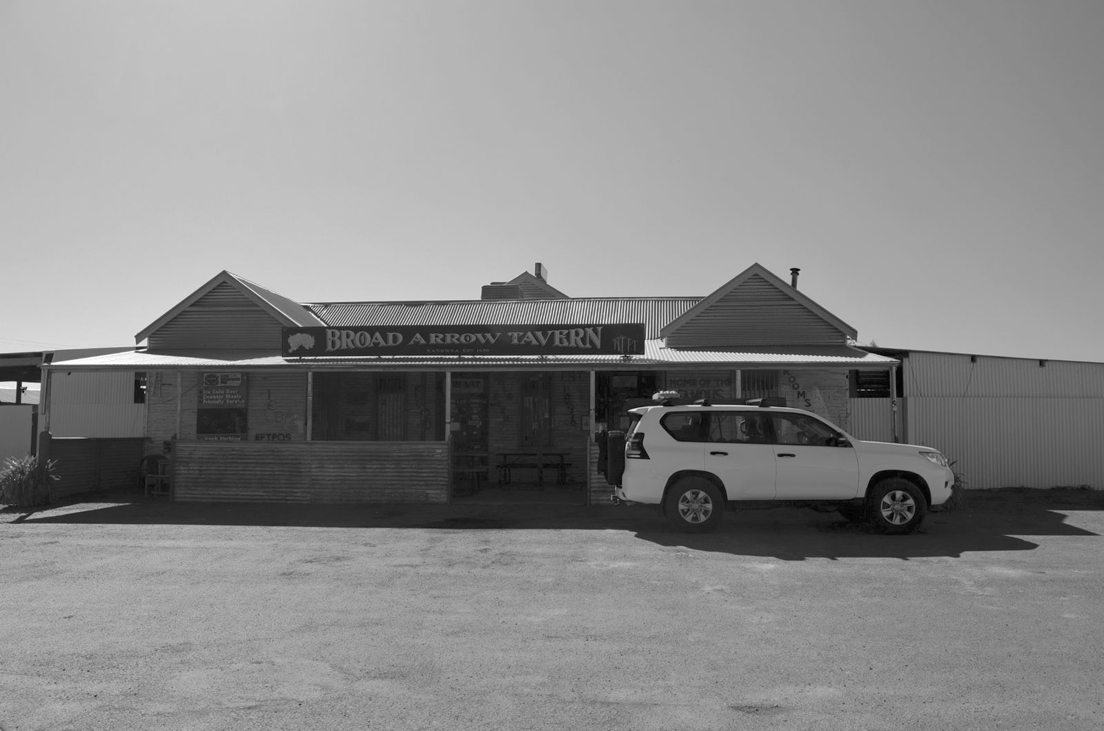 Kalgoorlie to Leonora: The Last Day of Never Having Swung a Detector Broad Arrow Tavern in black and white with a white Toyota Prado parked outside