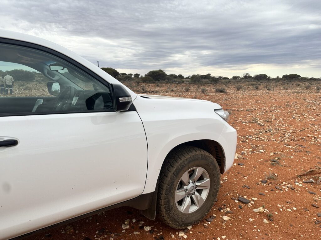 White Toyota Prado parked on red goldfields dirt scattered with white quartz near Leonora