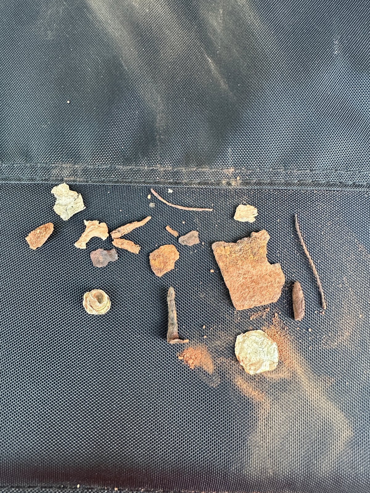 Did I Mention the Junk? Rusted tin, nails, wire and other scrap metal laid out on a black mat.